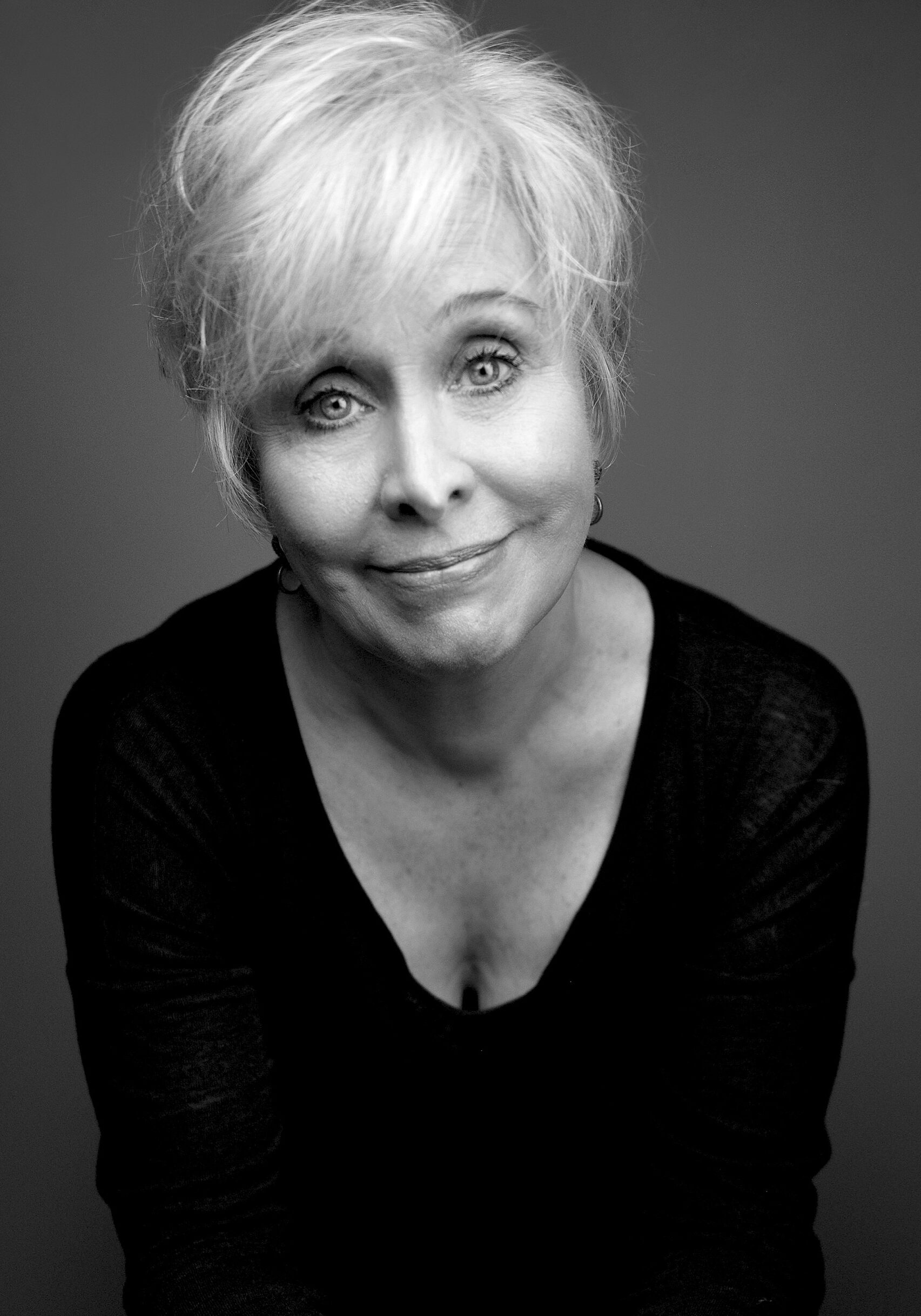 A black and white image of actress Nancy Opel wearing a black top and smiling softly at the camera.